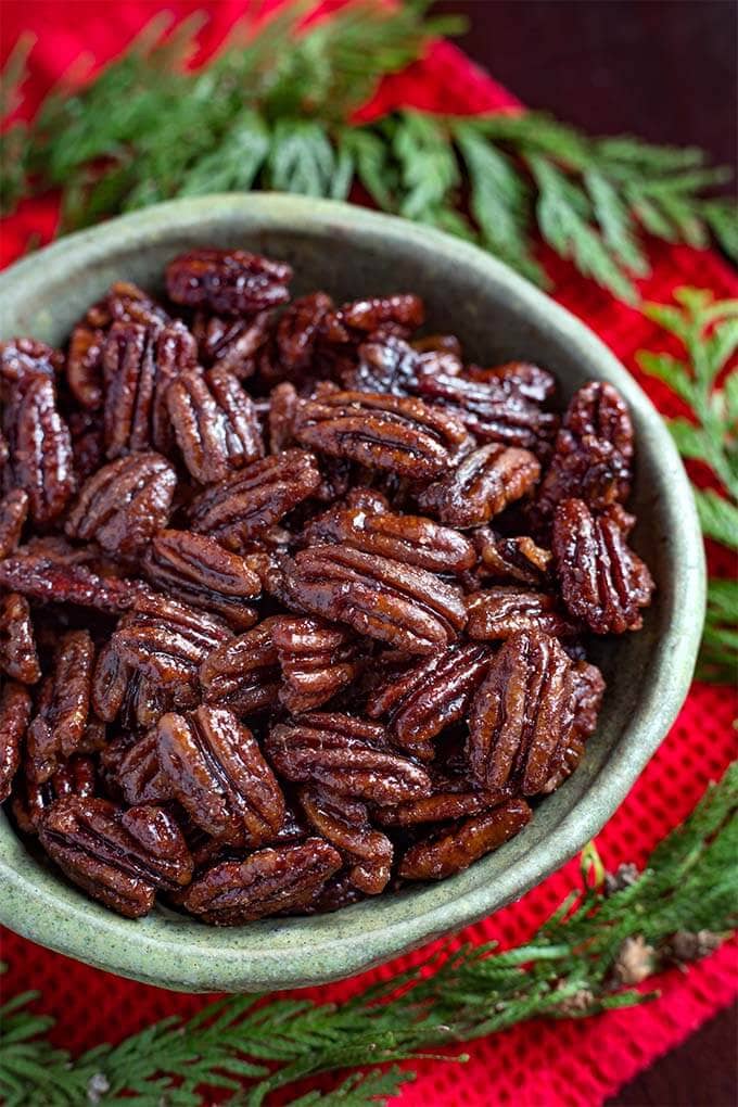 Maple Candied Pecans in a green bowl next to greenery