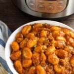 Sausage Gnocchi in a white bowl in front of a pressure cooker