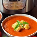 Fresh Tomato Basil Soup topped with croutons and fresh basil, in a white bowl