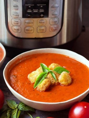 Fresh Tomato Basil Soup topped with croutons and fresh basil, in a white bowl