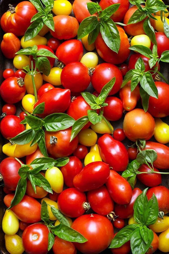 Several small red and yellow cherry tomatoes and fresh basil