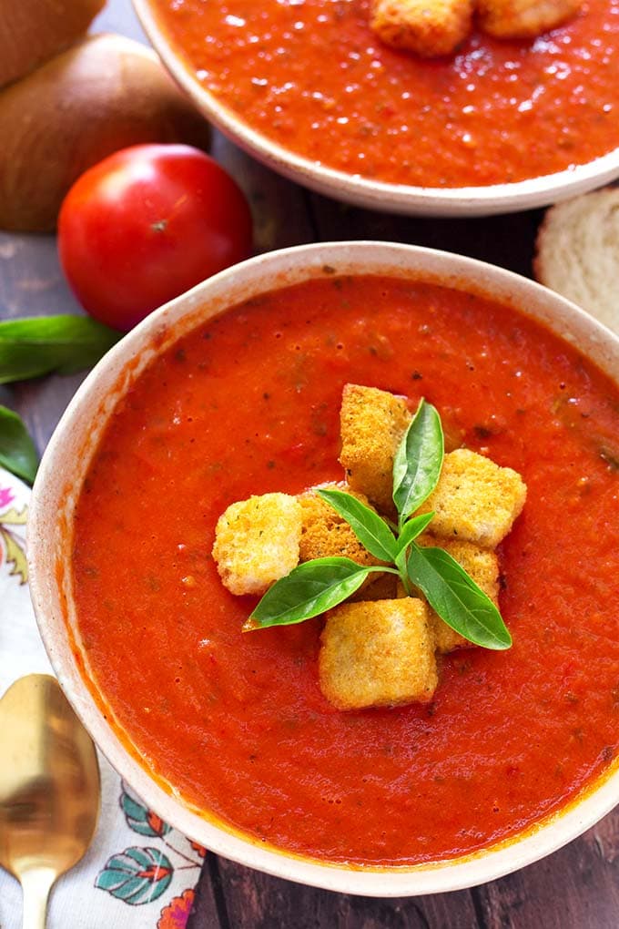 Top view of Fresh Tomato Basil Soup topped with croutons and fresh basil, in a white bowl
