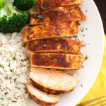 Sliced Baked Chicken Breast on a white plate with rice and broccoli