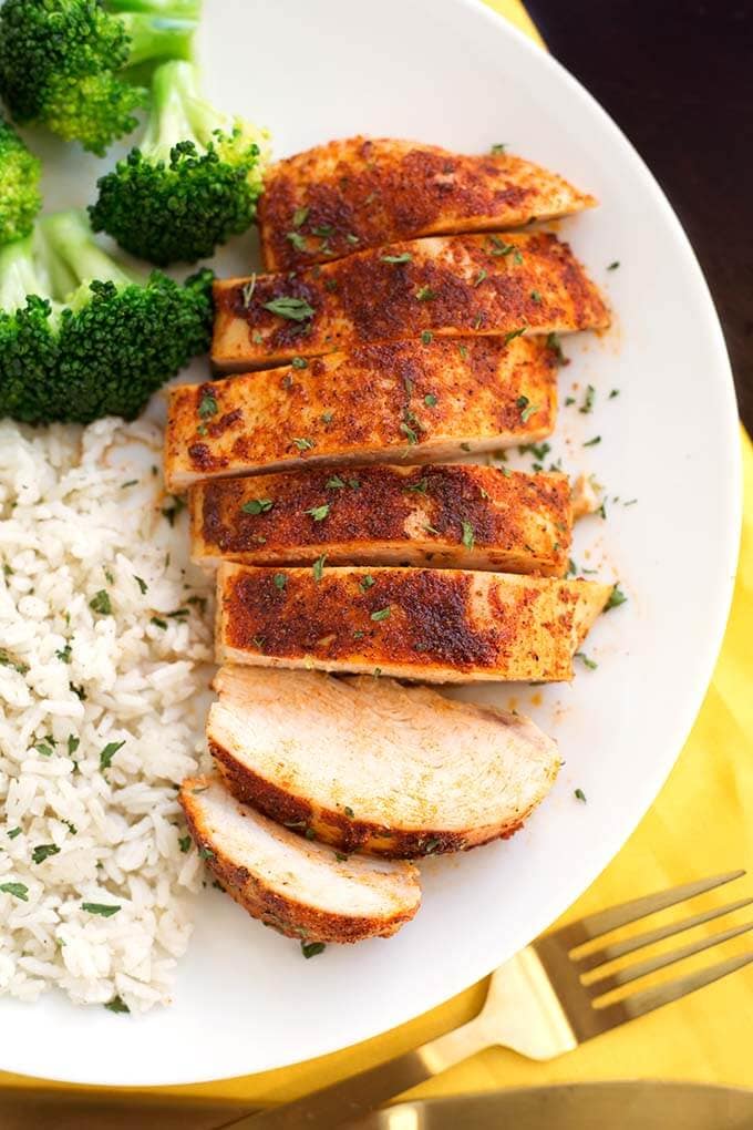 Sliced Baked Chicken Breast on a white plate with rice and broccoli