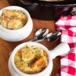 Two white bowls of Chicken and Dumplings in front of a slow cooker
