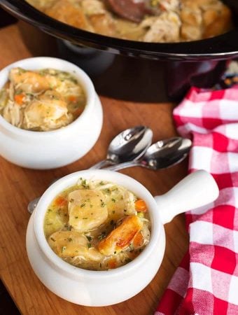 Two white bowls of Chicken and Dumplings in front of a slow cooker