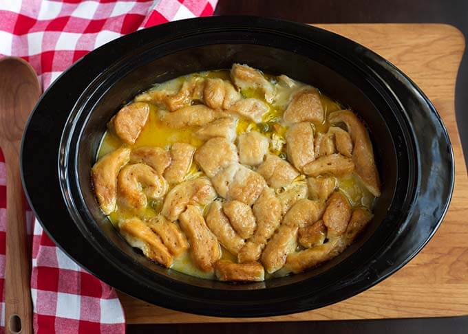 Top view of Chicken and Dumplings in a slow cooker next to a red gingham napkin