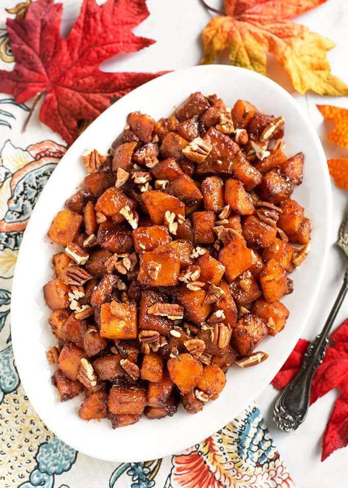 Top view of Cinnamon Roasted Butternut Squash on a white oblong platter on a floral napkin