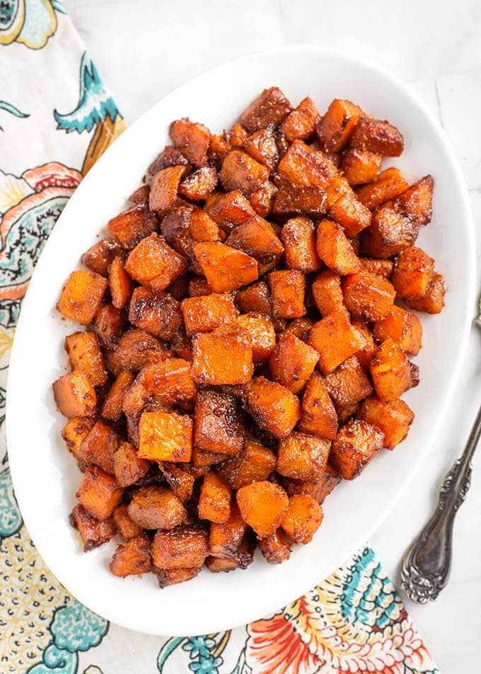 Top view of Cinnamon Roasted Butternut Squash on a white oblong platter on a floral napkin