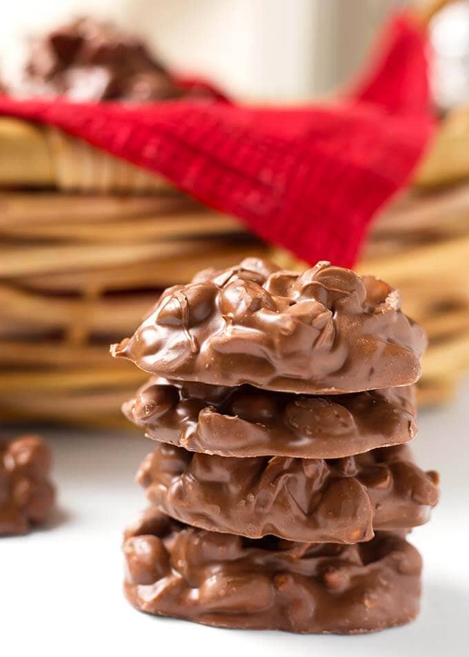 Four Chocolate Peanut Clusters candy stacked on top of each other in front of a wicker basket