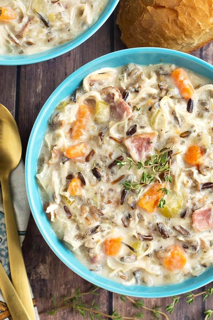 Creamy Chicken Wild Rice Soup in a blue bowl next to a gold spoon