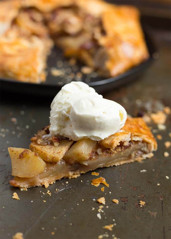 Slice of apple galette with vanilla ice cream in front of the remaining apple galette