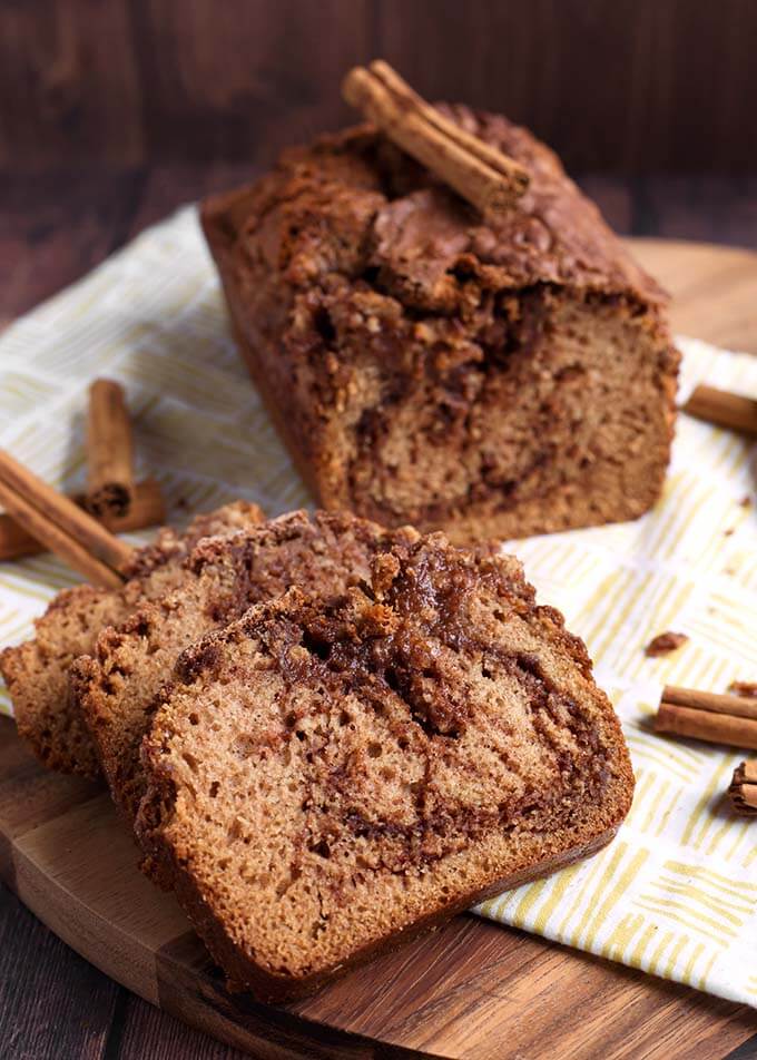 Slices of Nana's Easy Cinnamon Bread in front of loaf and cinnamon sticks