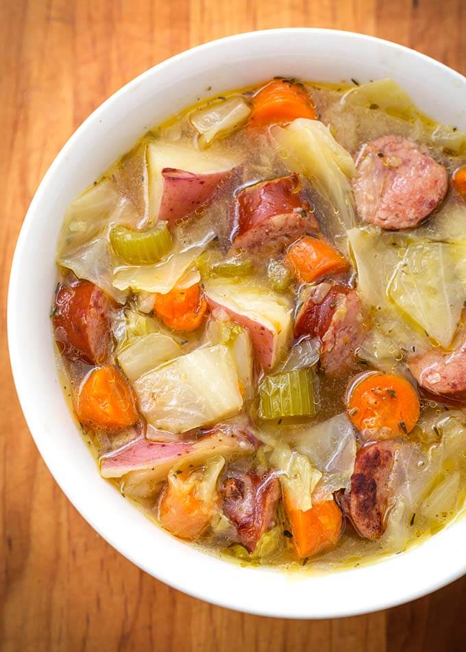 Kielbasa Cabbage Potato Soup in a white bowl on a wooden board