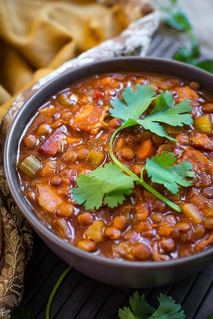 Lentil Soup in a gray bowl topped with a cilantro leaf stem