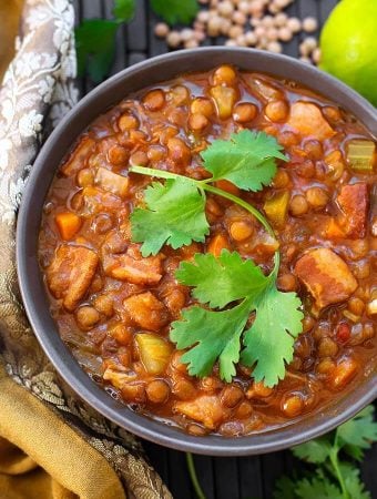 Lentil Soup in a gray bowl topped with a cilantro leaf