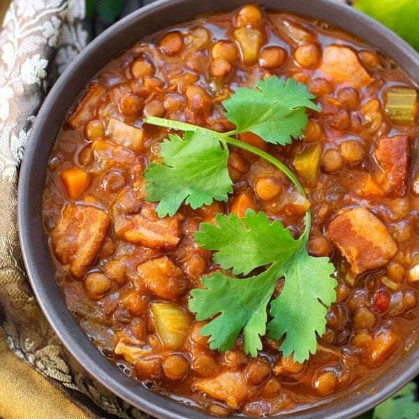 Lentil Soup in a gray bowl topped with a cilantro leaf