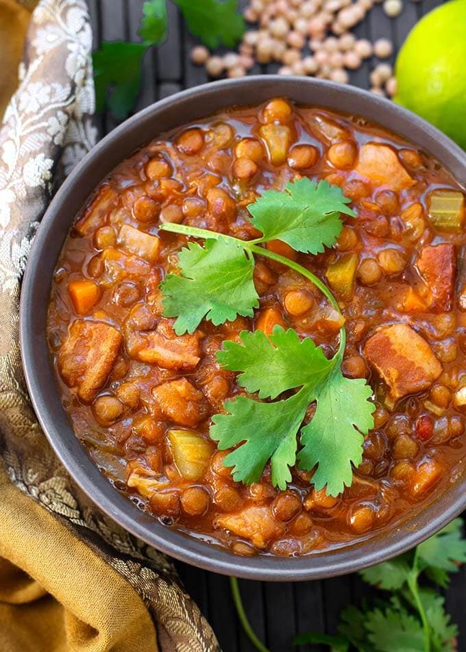 Lentil Soup in a gray bowl topped with a cilantro leaf