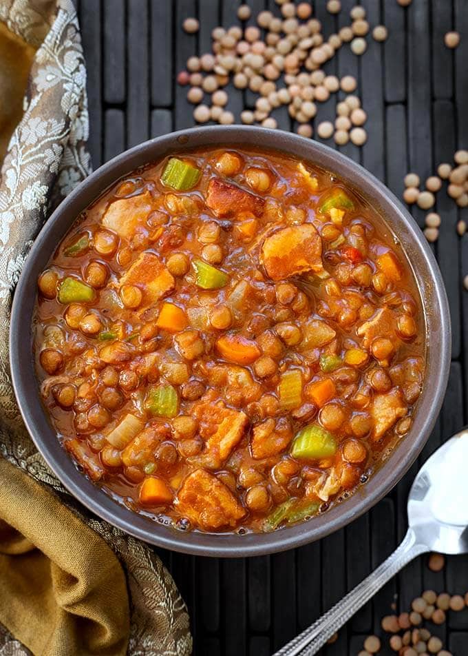 Lentil Soup in a gray bowl next to a silver spoon