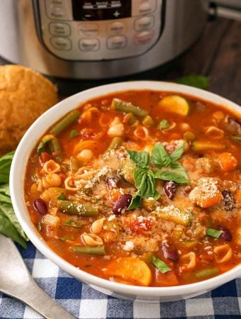 Minestrone Soup in a white bowl in front of a pressure cooker