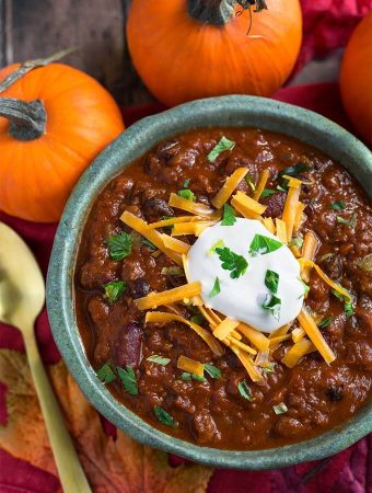 Pumpkin Chili topped with shredded cheese and sour cream in a turquoise bowl