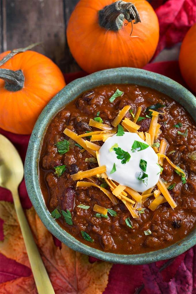 Pumpkin Chili topped with shredded cheese and sour cream in a turquoise bowl