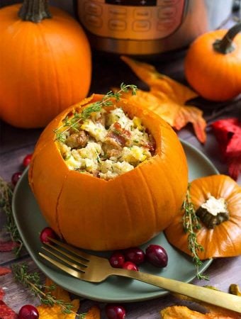 Stuffed pumpkin on a gray plate in front of fall leaves and a small pumpkin