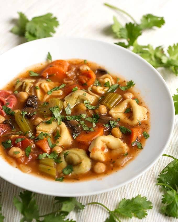 Vegetable Tortellini Soup in a white bowl next to fresh parsley