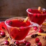 Two glasses of Spiced Cranberry Hot Toddy on a wooden board