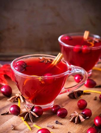 Two glasses of Spiced Cranberry Hot Toddy on a wooden board