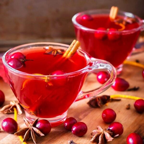 Two glasses of Spiced Cranberry Hot Toddy on a wooden board