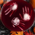 Three ice hands floating in Spooky Halloween Party Punch in a glass punch bowl