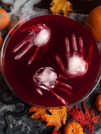 Three ice hands floating in Spooky Halloween Party Punch in a glass punch bowl