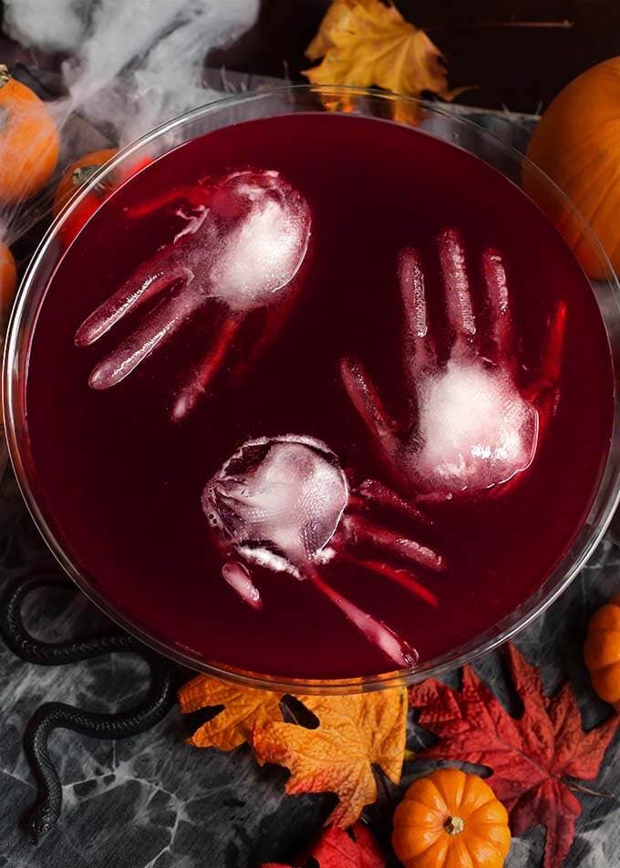 Three ice hands floating in Spooky Halloween Party Punch in a glass punch bowl