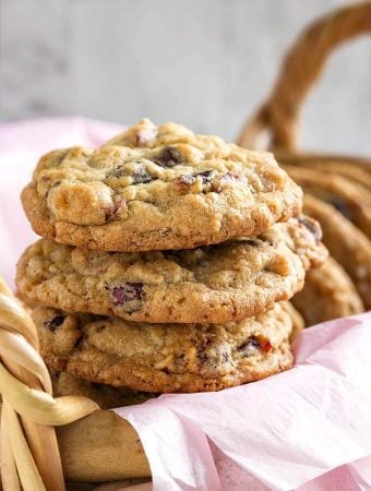 Closeup of three Cranberry Dark Chocolate Cookies stacked on a basket lined with a pink napkin