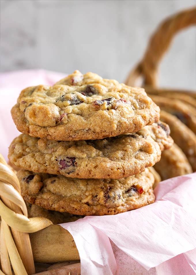 Closeup of  three Cranberry Dark Chocolate Cookies stacked on a basket lined with a pink napkin