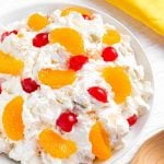 Creamy Cheesecake Fruit Salad in a white bowl on a white wood background