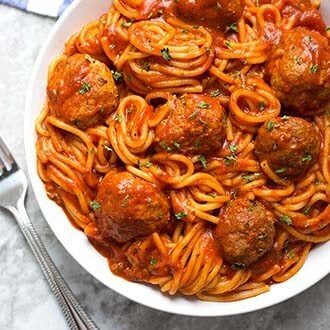 Spaghetti and Meatballs on a white plate next to a silver fork