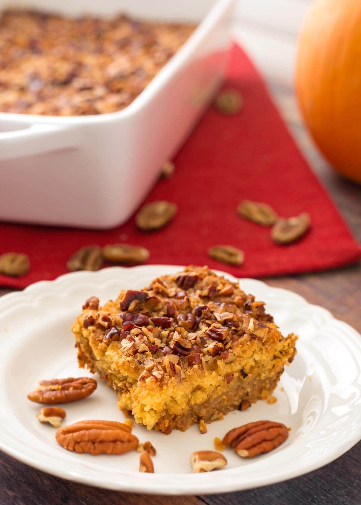 Slice of Pumpkin Pie Dump Cake on a white plate with pecan halves