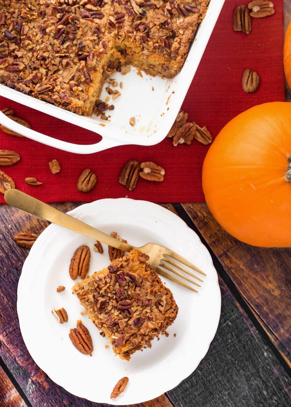 Slice of Pumpkin Pie Dump Cake on a white plate with pecan halves