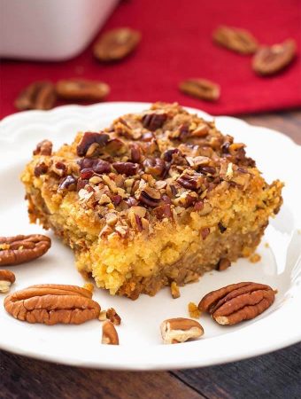 Slice of Pumpkin Pie Dump Cake on a white plate with pecan halves