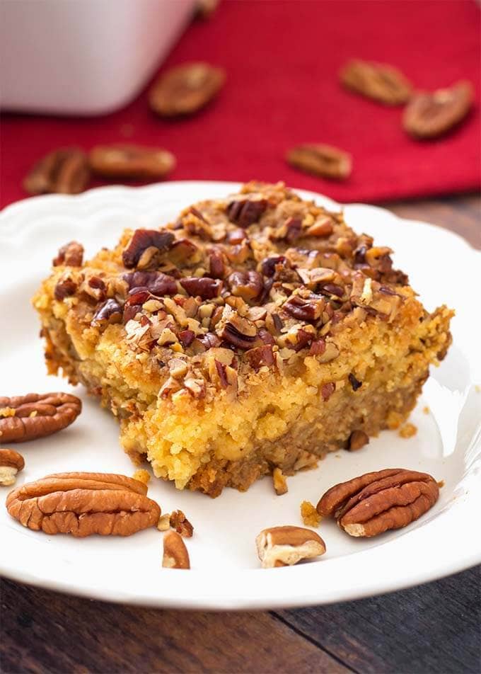 Slice of Pumpkin Pie Dump Cake on a white plate with pecan halves