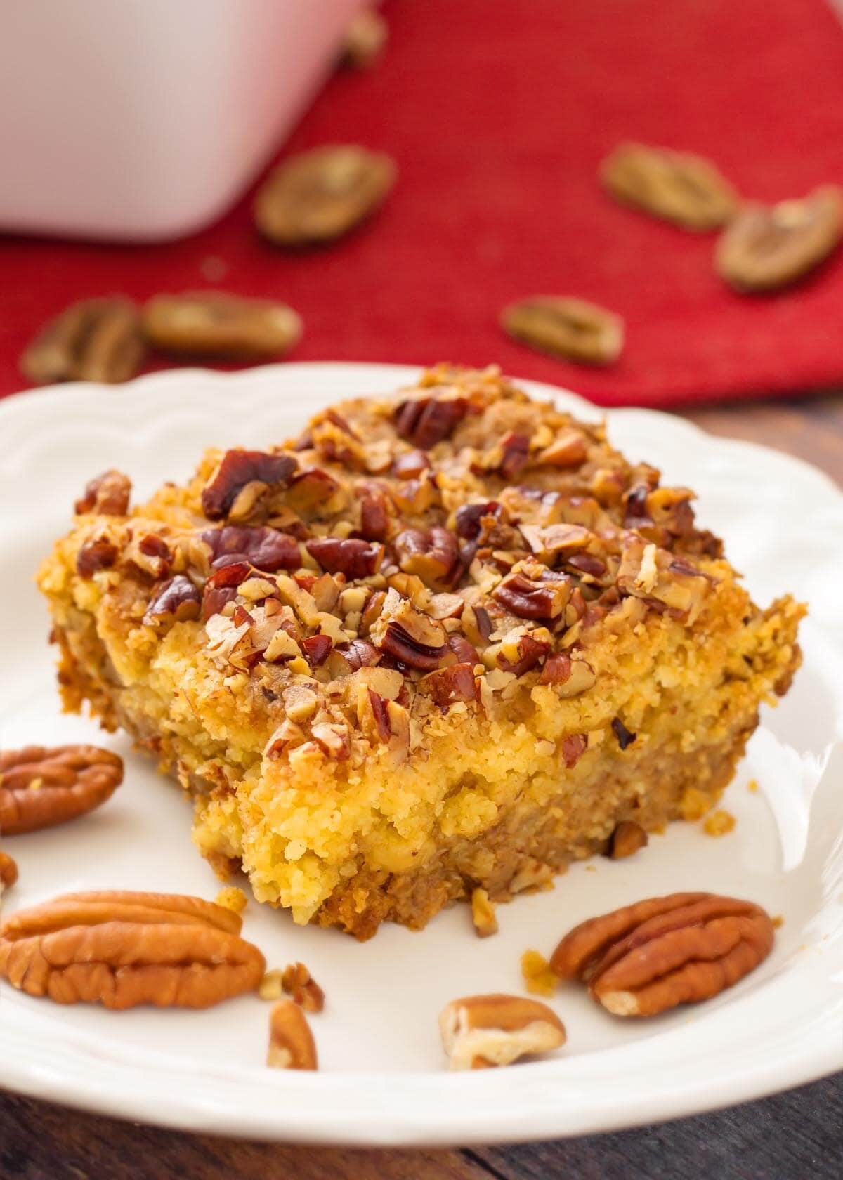 Slice of Pumpkin Pie Dump Cake on a white plate with pecan halves