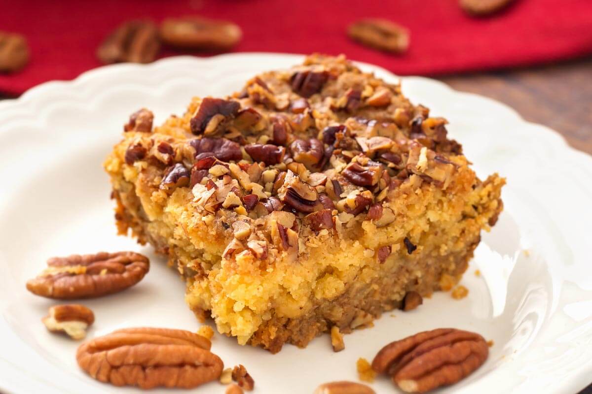 Slice of Pumpkin Pie Dump Cake on a white plate with pecan halves