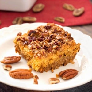 Slice of Pumpkin Pie Dump Cake on a white plate with pecan halves