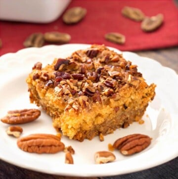 Slice of Pumpkin Pie Dump Cake on a white plate with pecan halves