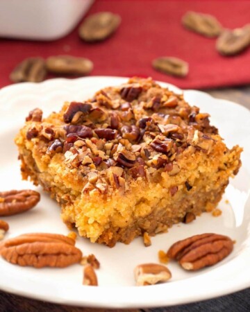 Slice of Pumpkin Pie Dump Cake on a white plate with pecan halves
