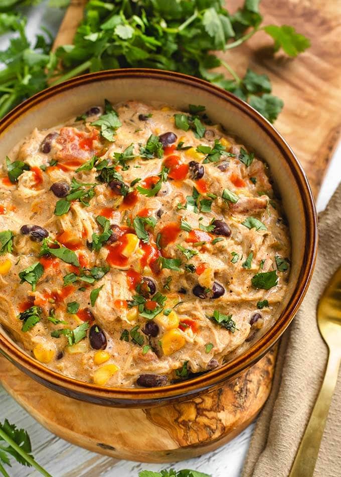 Creamy Chicken Chili in a beige bowl on a wooden board