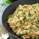 Brown Rice Pilaf in a black bowl next to two golden forks