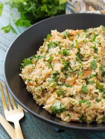 Brown Rice Pilaf in a black bowl next to two golden forks